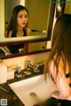 A woman looking at herself in the mirror in a bathroom.