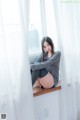 A woman sitting on a window sill in front of a window.