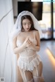 A woman wearing a white lingerie and a veil.