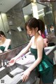 A woman in a green dress standing in front of a mirror.