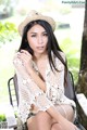 A woman sitting on a chair wearing a straw hat.