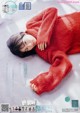 A woman in a red sweater laying on a bed.