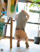 A woman in a gray shirt and white panties crouching down on the floor.