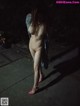 A naked woman walking down a sidewalk at night.