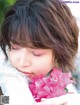 A young girl holding a pink flower in her hands.