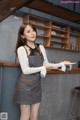 a woman standing in front of a counter wearing a gray apron