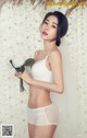 A woman in a white lingerie holding a white rose.