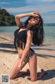 A woman in a bikini sitting on the beach.