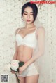 A woman in a white lingerie holding a bouquet of flowers.