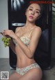 A woman in a bikini holding a bunch of grapes.