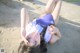 A young girl laying on the sand with her hands on her head.