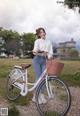 A woman standing next to a white bicycle with a basket.