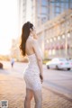 A woman in a white dress is walking down the street.