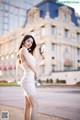 A woman in a white dress holding a pair of sunglasses.