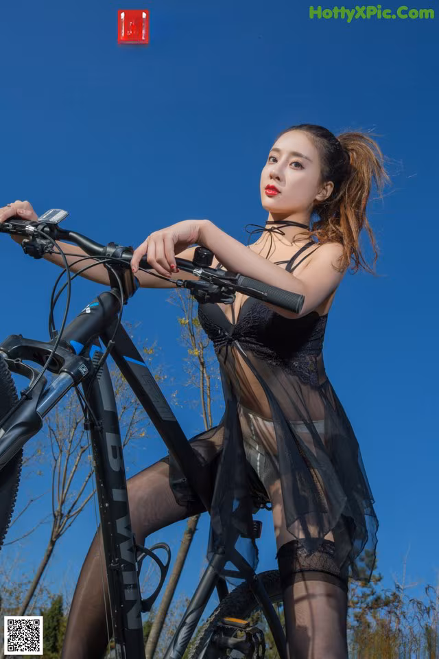 A woman in lingerie riding a bike on a sunny day.