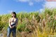 A naked woman standing in a field of tall grass.