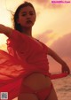 A woman in a red bikini standing on the beach.