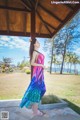 A woman in a colorful dress standing under a gazebo.