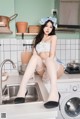 A woman sitting on top of a washing machine in a kitchen.