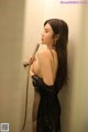 A woman in a black dress standing in a shower.