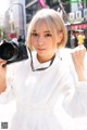 A woman in a white dress holding a camera.