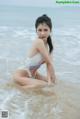 A woman in a white bikini sitting in the water.