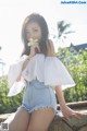 A woman in a white top and denim shorts posing for a picture.