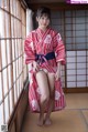 A woman in a red and white kimono posing for a picture.