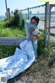 A woman in pajamas holding a teddy bear next to a fence.