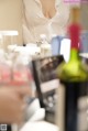 A woman sitting at a table with a bottle of wine.