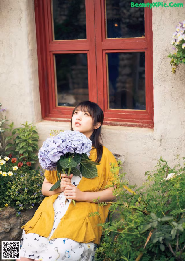 A woman sitting on a bench holding a bunch of flowers.