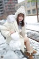 A woman sitting on a train track holding a snowman.