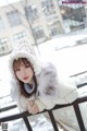 A woman in a white coat and hat leaning on a railing.