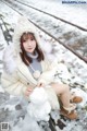 A woman sitting on a train track holding a snowman.