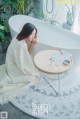 A woman sitting in a bathtub next to a table.