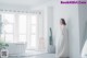 A woman in a white dress standing in a room.