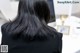 A woman with long black hair standing in front of a computer.