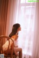 A woman sitting on a chair in front of a window.