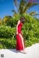 A woman in a red dress standing on a beach.