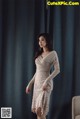 A woman standing in front of a blue curtain.