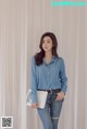 a woman in a blue shirt and jeans posing for a picture