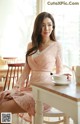 A woman sitting at a table with a cup of coffee.