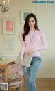 a woman in a pink sweater and jeans posing for a picture