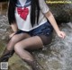 A woman in a school uniform is sitting in the water.