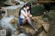 A woman sitting on a rock next to a stream.