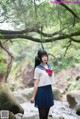 A woman in a school uniform standing in front of a stream.