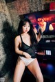 A woman in lingerie holding a microphone in front of a television.
