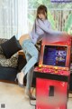 A woman sitting on top of a table next to a video game machine.