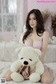 A woman sitting on a bed holding a teddy bear.