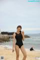 A woman in a black swimsuit standing on a beach.